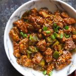 Aerial shot of chilli chicken in a white serving bowl.