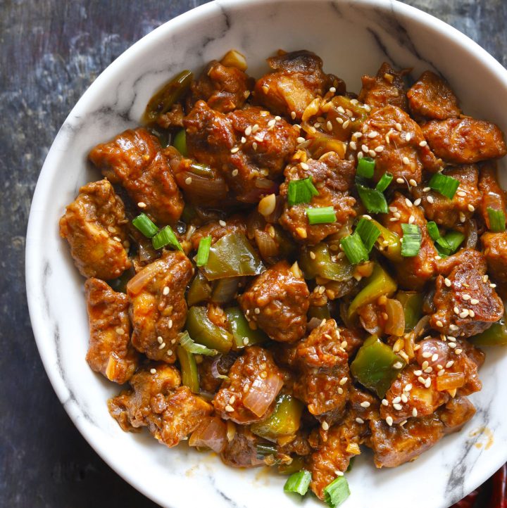 Aerial shot of chilli chicken in a white serving bowl.