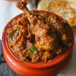 side close up shot of Chettinad chicken masala in a traditional earthen serveware