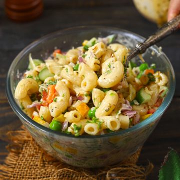 side shot of macaroni salad in a bowl with a serving spoon