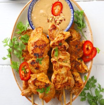 aerial shot of chicken satay on a platter with peanut dipping sauce.