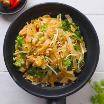 aerial shot of chicken pad thai in a black serving bowl