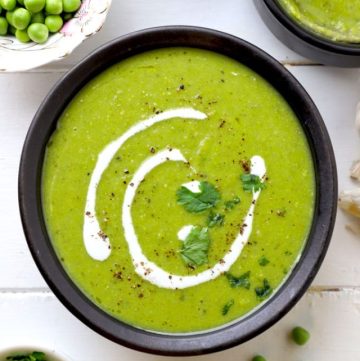 aerial shot of green pea soup served in a black ceramic bowl