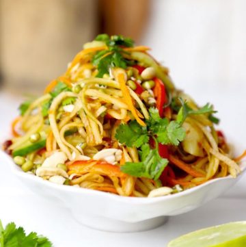 side shot of green papaya salad stacked on a white bowl