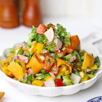 side shot of fattoush salad stacked on a white ceramic platter