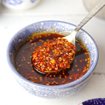 side angle shot of chilli oil in a blue ceramic bowl with the spoon