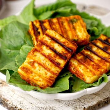 side shot of grilled paneer served on lettuce leaves