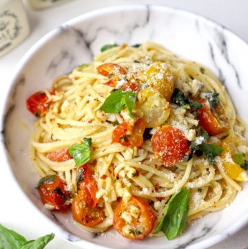 side close up shot of cherry tomato pasta in a white ceramic bowl