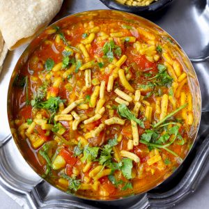 aerial shot of sev tamatar ki sabji in a steel bowl