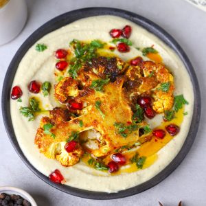 aerial shot of cauliflower steak with hummus on a black platter